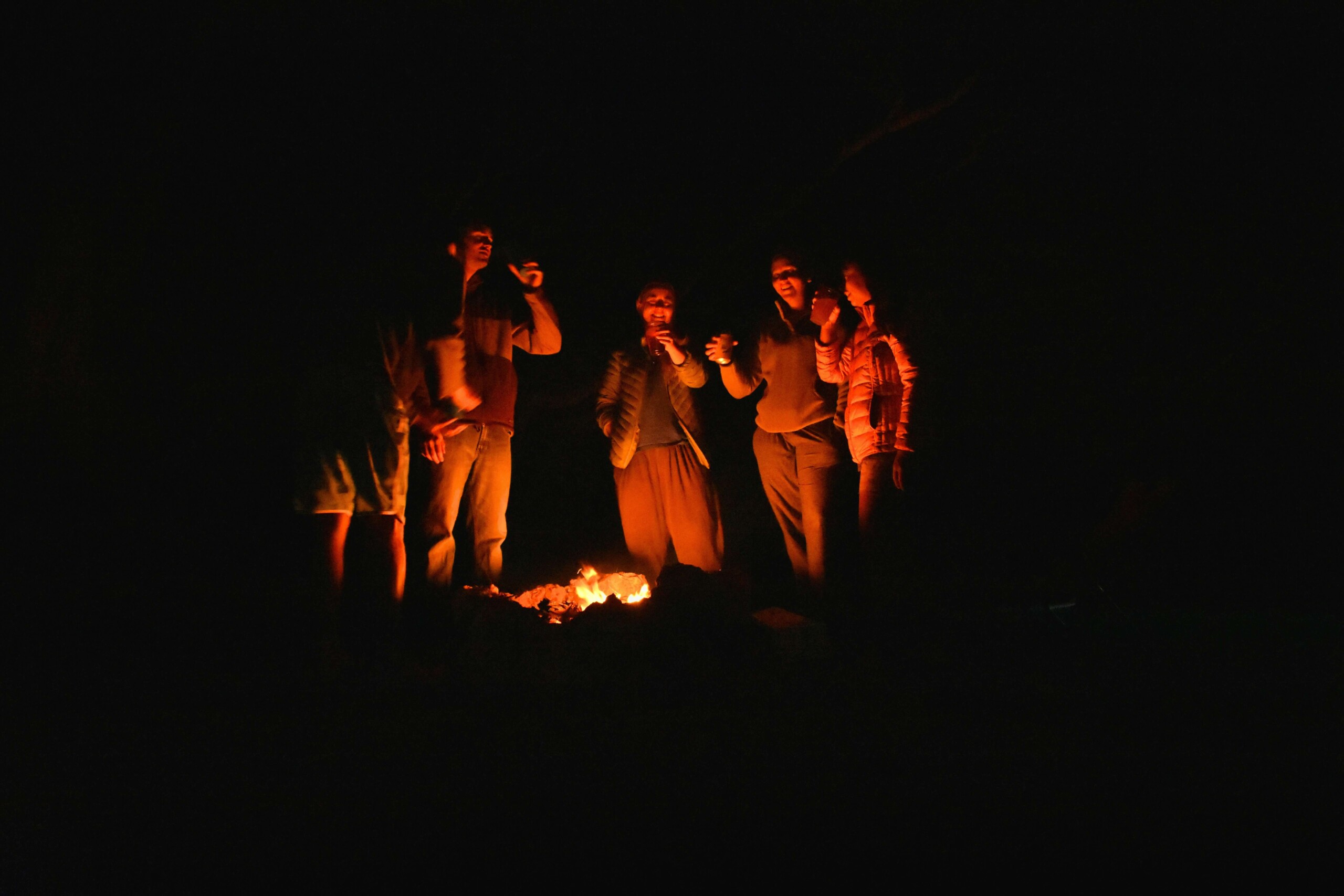 Image of a group of teens standing around a campfire. This image represents the connection teens can have with camp. Find them extra support with teen therapy in Farmington Hills, MI.