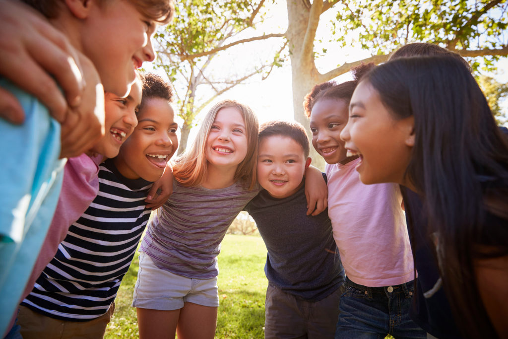 Group of children huddle as they smile at one another. They are part of Banana Splits, a children of divorce support group in West Bloomfield, MI. Therapyology offers therapy for children of divorce in West Bloomfield, MI. Contact us to get in touch with a child divorce therapist today.