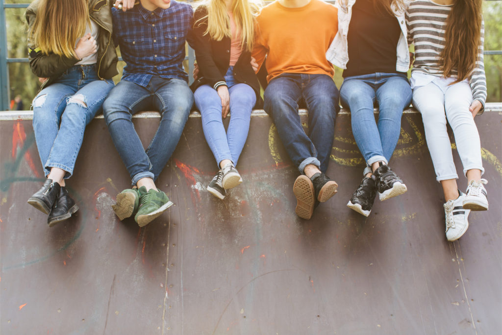 A group of teens sit with feet crossed as they hand off a wall. This could symbolize the bonds made from summer camp in California. Contact Camp Therapyology to learn more about our camp for teens in Michigan and more.