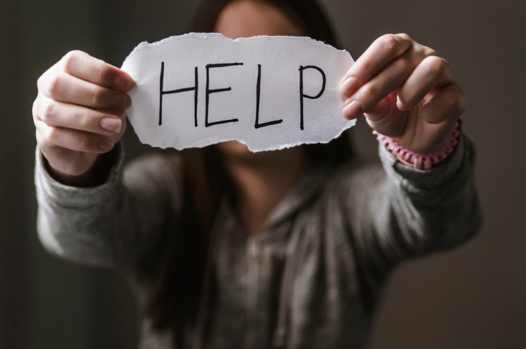 A teen holds a help sign in front of their face. Teenage counseling in West Bloomfield, MI can offer support. Contact a teenage counselor in West Bloomfield, MI to learn more about online therapy for teens in Michigan and .