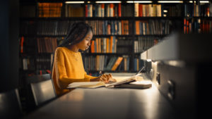 A student writes something while studying intently in a library. Life transitions counseling in Michigan can help you cope with college. Learn more about transitions counseling in West Bloomfield, MI today!