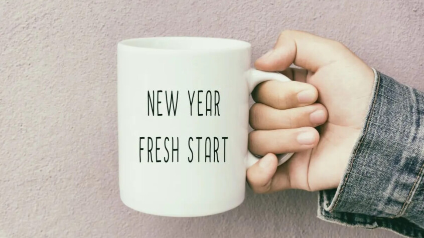An image of a hand holding a mug with the words " new year fresh start" on the side for Therapyology. We offer life transitions counseling in Michigan, and California. Contact us to learn more about life transitions counseling in West Bloomfield, MI today!