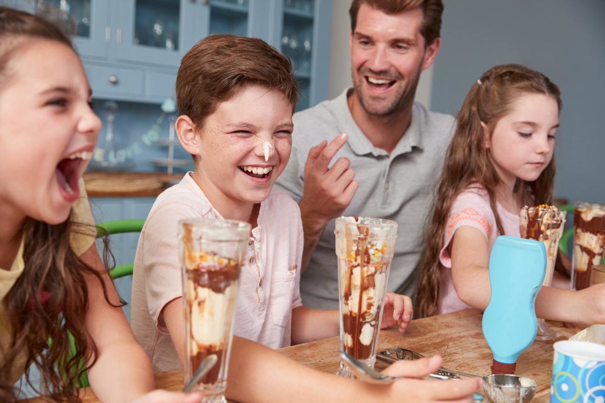 A father smiles as his three kids enjoy tall milkshakes. This could represent the joy that child divorce therapy in West Bloomfield, MI can help cultivate. Contact a child therapist for divorce in West Bloomfield, MI to learn more today! | 48322 | 94118